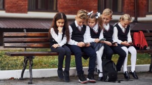 Jakie ubrania do szkoły ubrać? Na zdjęciu dzieci w szkole w mundurkach.